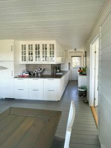 cocina con armarios blancos y suelo de madera en Cozy Cabin With Sea View And Two Terraces, en Tjøme