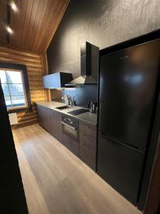 a kitchen with a black refrigerator and a stove at Arvoneliöt Lomahimos 18 in Jämsä