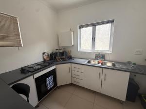 Sunny Snooze Holiday Home في جودوود: مطبخ صغير مع حوض وموقد +3 صور