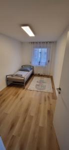 een lege kamer met een bed en een houten vloer bij Wunderschönes Haus mit 3 Schlafzimmern in Crailsheim