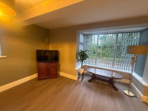 ein Wohnzimmer mit einem Tisch, einem TV und einem Fenster in der Unterkunft Rose Cottage by Sasco in Blackpool