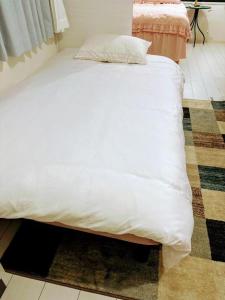 a bed with a white comforter on top of a room at The Akasaka roppongi Central Stay in Tokyo