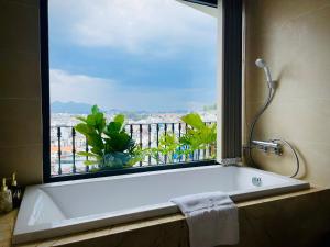 a bath tub in a bathroom with a large window at Maccal Boutique Hotel Dalat in Da Lat