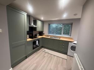 a kitchen with green cabinets and a washing machine at Rose Cottage by Sasco in Blackpool