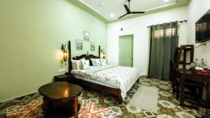 a bedroom with a bed and a table and a desk at The Gulmohar Villa in Tājganj +173 photos