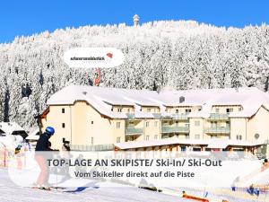 a person on skis standing in front of a ski lodge at FeWo Schwarzwaldschick Feldberg I Direkt an der Piste I Whirlwanne I Tiefgarage I Skipass vergünstigt in Feldberg
