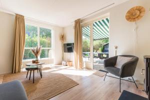 Cozy No 2 Wellness Villa Hottub, Sauna en houtkachel في Hernen: غرفة معيشة مع كرسي وطاولة