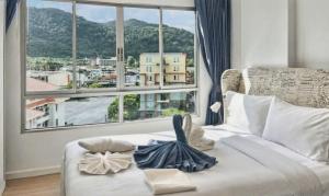 a bedroom with a bed with a large window at Dcondo Kathu - Top Floor 1 Bdr Condo with shared Pool in Kathu