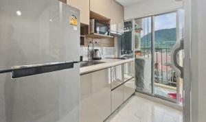 a kitchen with a stainless steel refrigerator and a window at Dcondo Kathu - Top Floor 1 Bdr Condo with shared Pool in Kathu