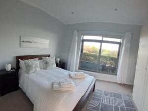 a white bedroom with a bed and a window at Romansbaai Beach House in Gansbaai +31 photos