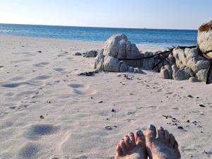 a person laying on a beach with their toes in the sand at Romansbaai Beach House in Gansbaai