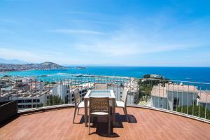 Una mesa y sillas en un balcón con vista al mar. en Pine City Residence, en Kusadasi
