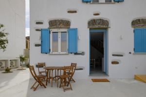 a table and chairs on a patio with blue shutters at Stylish villa Antika close to the shops and restaurants in Korissia, Kea in Korissia