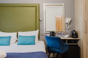 a hotel room with a bed and a blue chair at The Porchester Hotel in London