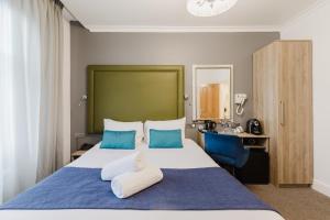 a bedroom with a large bed with blue and white pillows at The Porchester Hotel in London