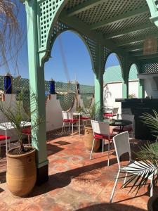 a patio with chairs and tables and a green pergola at Riad Jadis in Marrakesh