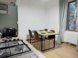 VECCHIA FERROVIA Orvieto Apartment في أورفييتو سكالو: مطبخ مع طاولة مع كراسي وموقد