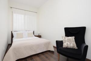 a bedroom with a bed and a black chair at Pool & Cozy Apartment Warszawa Bukowińska by Solarento in Warsaw