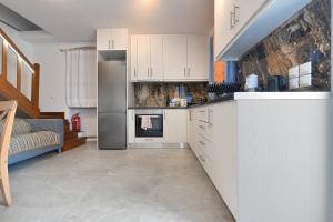 a kitchen with white cabinets and a refrigerator at Stylish villa Antika close to the shops and restaurants in Korissia, Kea in Korissia +17 photos