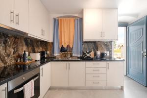 a kitchen with white cabinets and a blue door at Stylish villa Antika close to the shops and restaurants in Korissia, Kea in Korissia