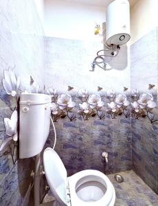 baño con aseo con flores en la pared en Majestic Inn Home Stay, en Varanasi
