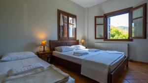 two beds in a room with a window and two bedsitures at Stilvi in Tsagarada