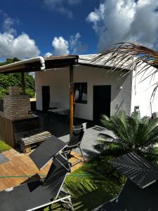 un patio con sillas y una casa con una palmera en Latinos Casa with pool, en Maragogi
