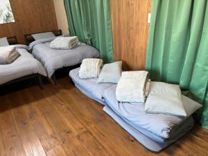 松山一棟貸し宿Tsuji في ماتسوياما: ثلاثة أسرة في غرفة مع ستائر خضراء