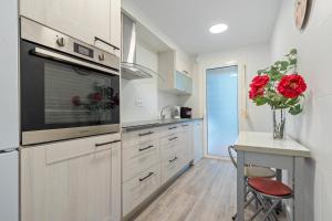 a kitchen with white cabinets and a vase of red roses at Hauzify I Apartament Kempenland in Salou +11 photos