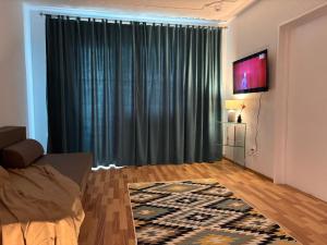 ein Wohnzimmer mit einem großen Vorhang und einem TV in der Unterkunft Rent Apartments Barlad 2 in Bîrlad