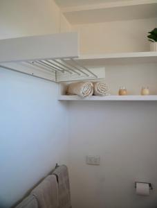 Habitación con paredes blancas y estanterías con toallas en Harbour Lane Stay, en Geraldton