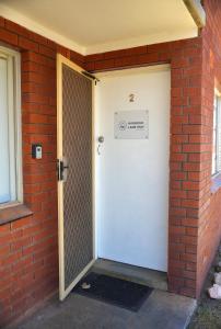 una puerta blanca con un letrero junto a una pared de ladrillo en Harbour Lane Stay, en Geraldton