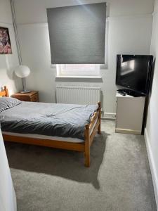 a bedroom with a bed and a flat screen tv at Spacious 4 bedroom apartment with parking in Leavesden Green
