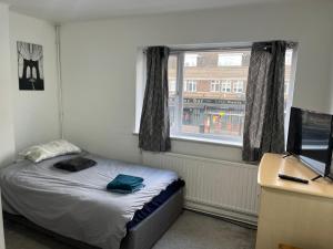 a small bedroom with a bed and a window at Spacious 4 bedroom apartment with parking in Leavesden Green