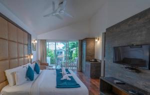 a hotel room with a bed with a flat screen tv at Trinantara Resort & Spa in Kālāgarh