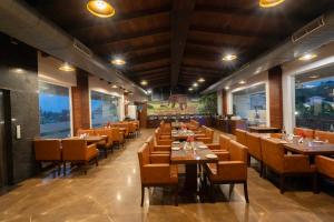 a restaurant with wooden tables and chairs and windows at Trinantara Resort & Spa in Kālāgarh