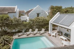 a swimming pool with lounge chairs and a house at Gonana Guesthouse in Paternoster