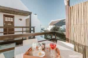 a table with glasses of wine on a balcony at Gonana Guesthouse in Paternoster