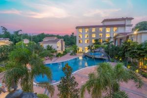 a view of a hotel with a pool and palm trees at Trinantara Resort & Spa in Kālāgarh