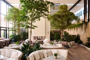 Un vestíbulo con sofás blancos, árboles y plantas. en 1 Hotel Copenhagen, en Copenhague