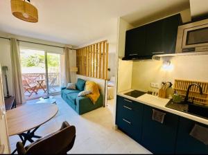 a kitchen and living room with a blue couch and a table at T1 bis rénové, clim et confort - Saint Raphaël in Saint-Raphaël