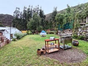 a backyard with a table and a grill in the grass at Huilka Mayu in Urubamba