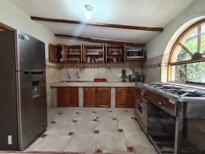 a kitchen with wooden cabinets and a stainless steel refrigerator at Huilka Mayu in Urubamba