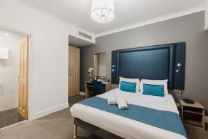 a bedroom with a large bed with blue pillows at The Porchester Hotel in London