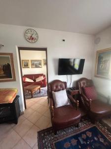 a living room with two chairs and a flat screen tv at Casa Belvedere in Lizzano in Belvedere