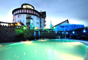 a swimming pool in front of a building at night at Hotel Belvedere in Braşov