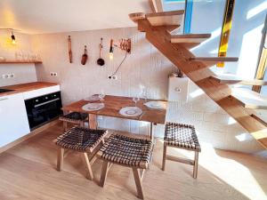 a kitchen with a wooden table and chairs and a staircase at L'appart du Yeti, cocon rénové avec goût, multipass été, ménage et linges compris in Les Gets
