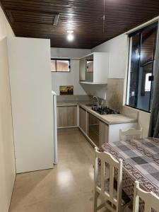 Una cocina con un refrigerador blanco y una mesa. en Pousada Mizuyama, en Praia do Rosa