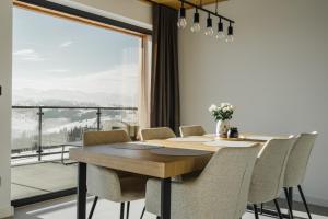 a dining room with a table and chairs and a large window at Tatres Bachledówka in Czerwienne