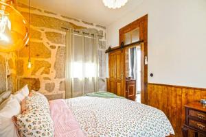 Un dormitorio con una cama y una pared de piedra. en Refúgio Rústico - Exclusivo, en Favaios